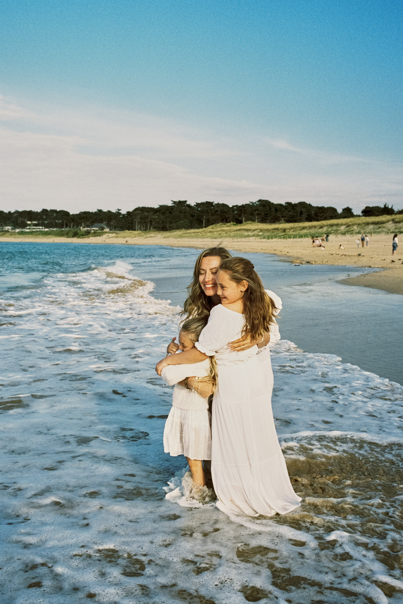 Maman serrant ses enfants dans ses bras au bord de la mer pendant une séance photo famille