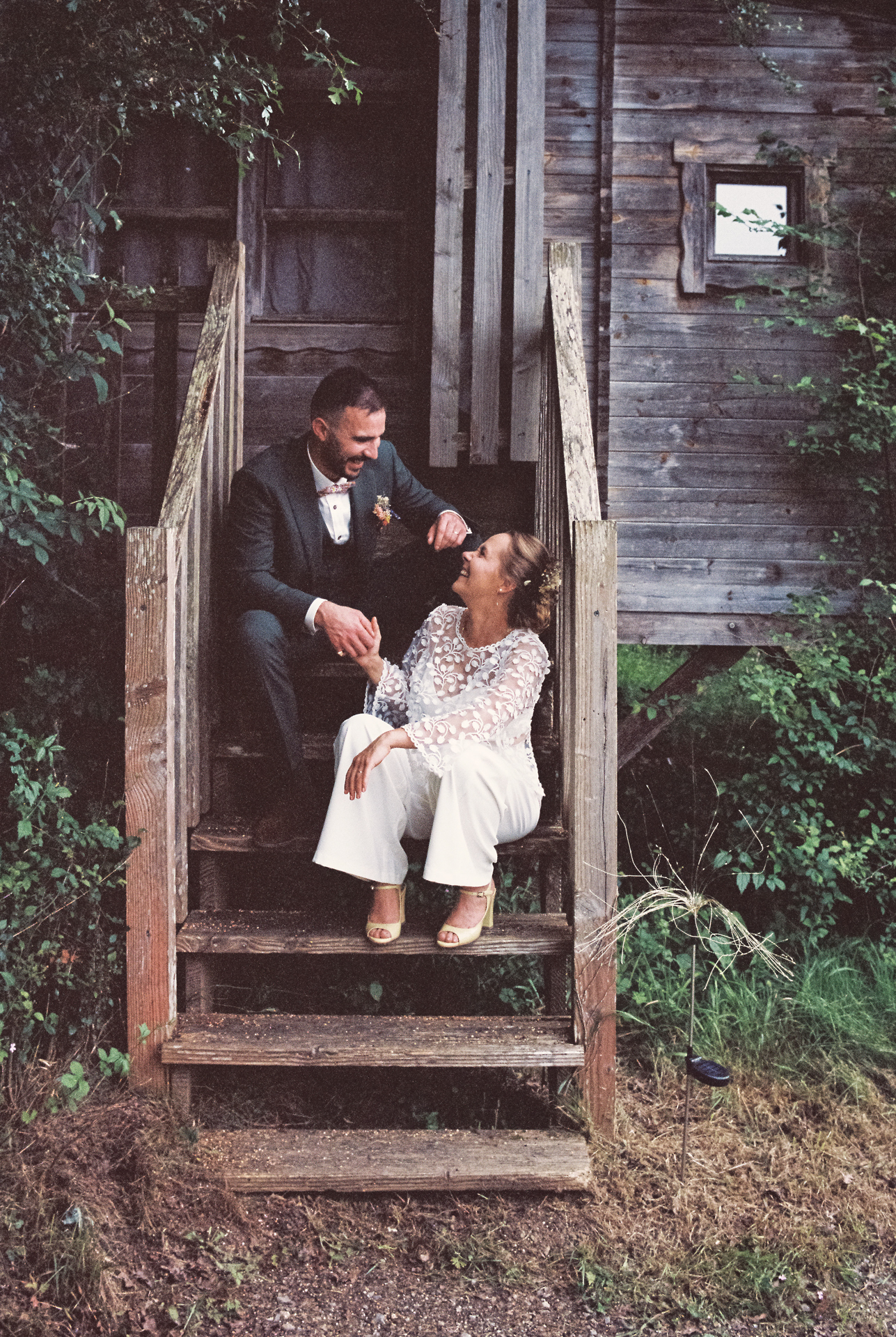 Couple de mariés assis devant une cabane en bois lors de leur mariage à Échologia