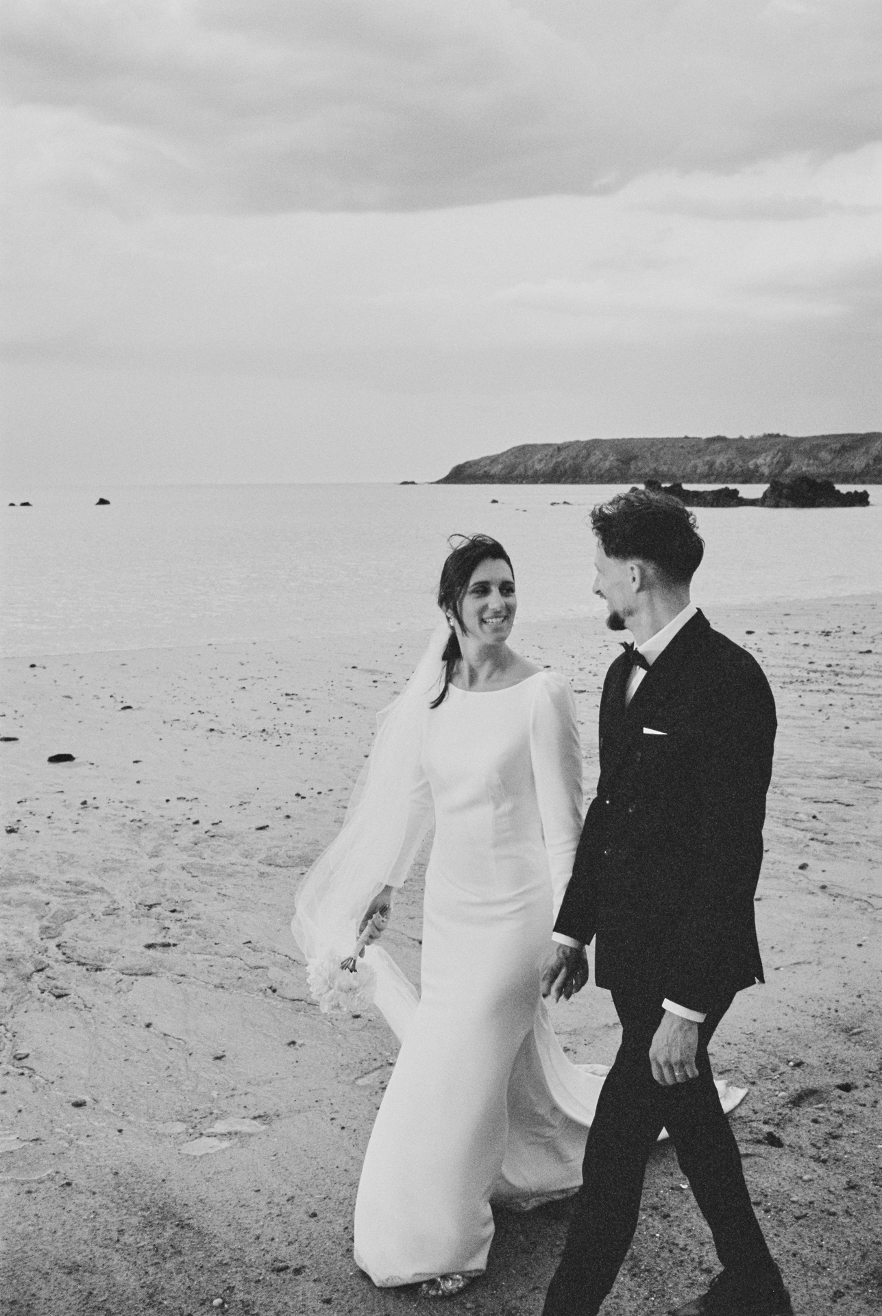 Couple de mariés marchant sur une plage lors de leur reportage de mariage