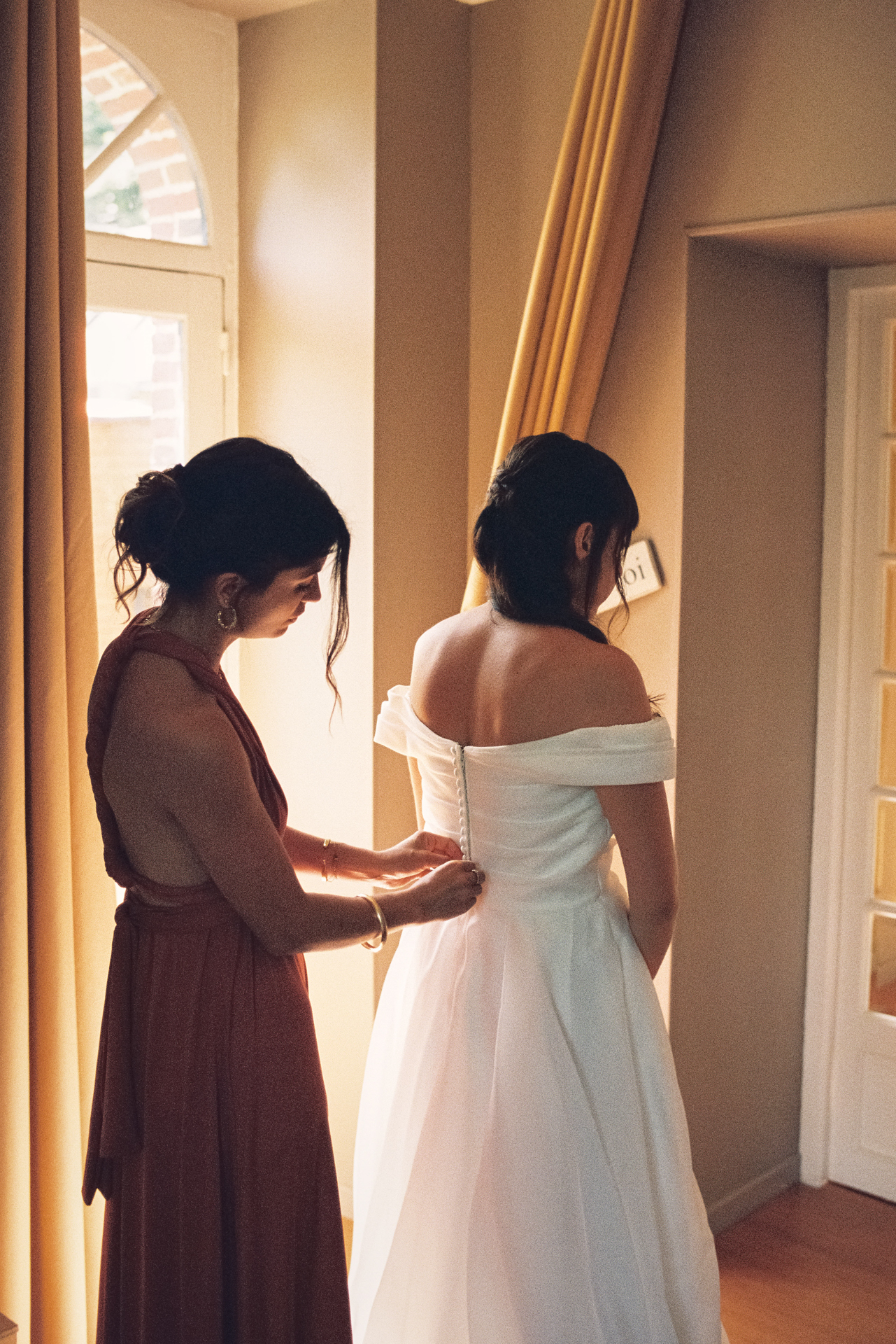 Proche aidant la mariée à ajuster sa robe pendant un reportage photo mariage