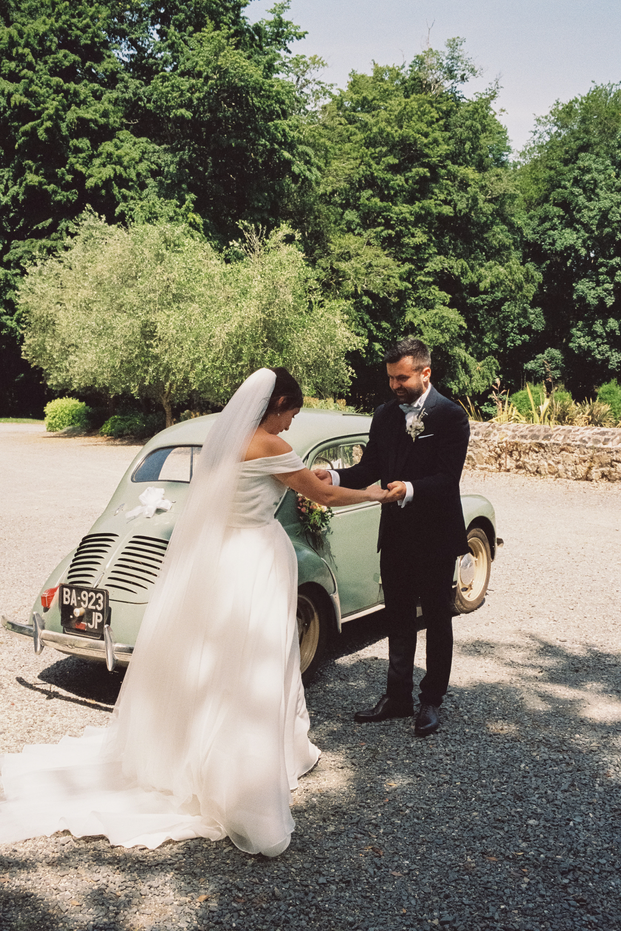 Mariés photographiés près d’une voiture ancienne pendant leur mariage au Château du Lattay