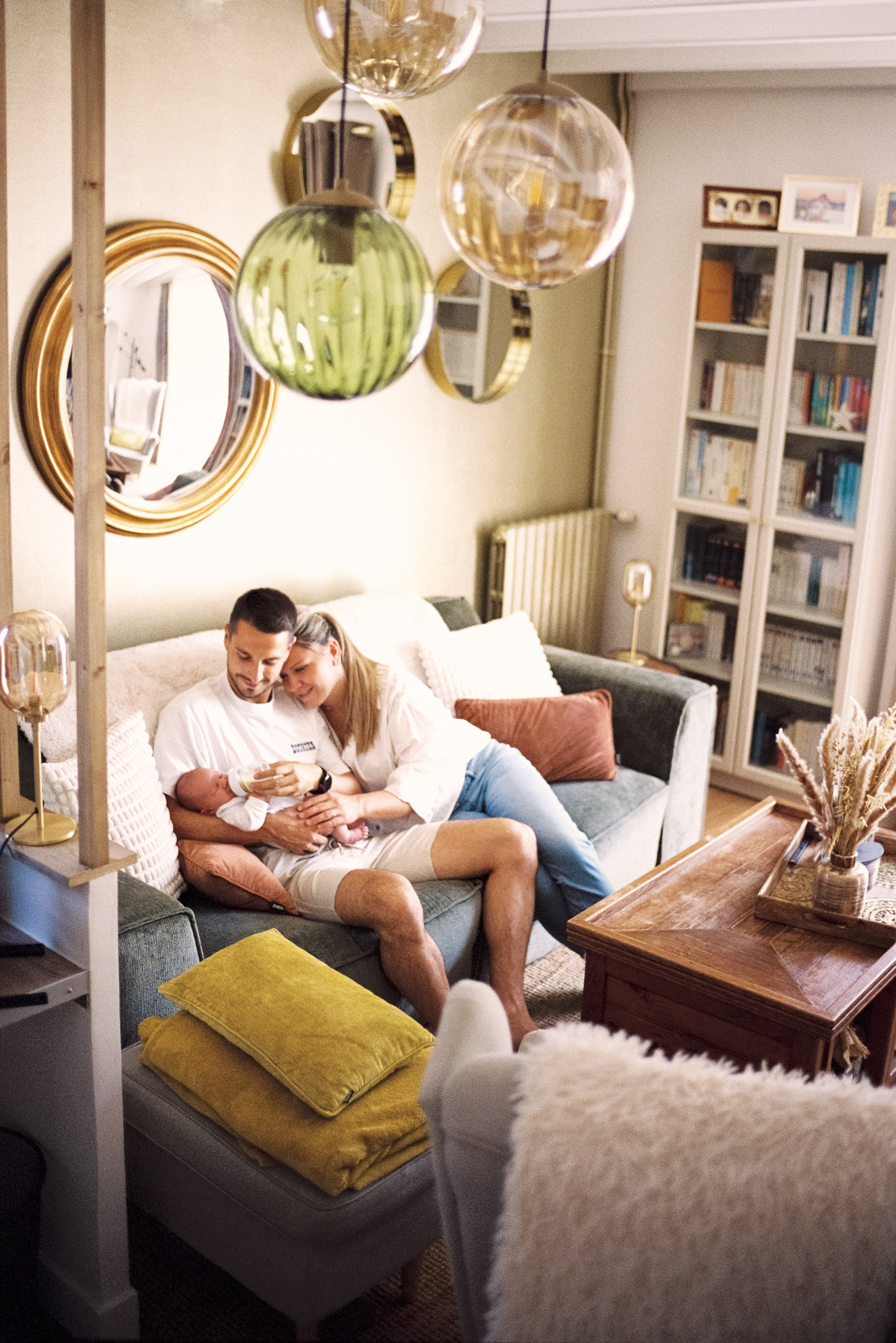 Parents assis sur leur canapé avec leur nouveau-né lors d’une séance naissance à domicile