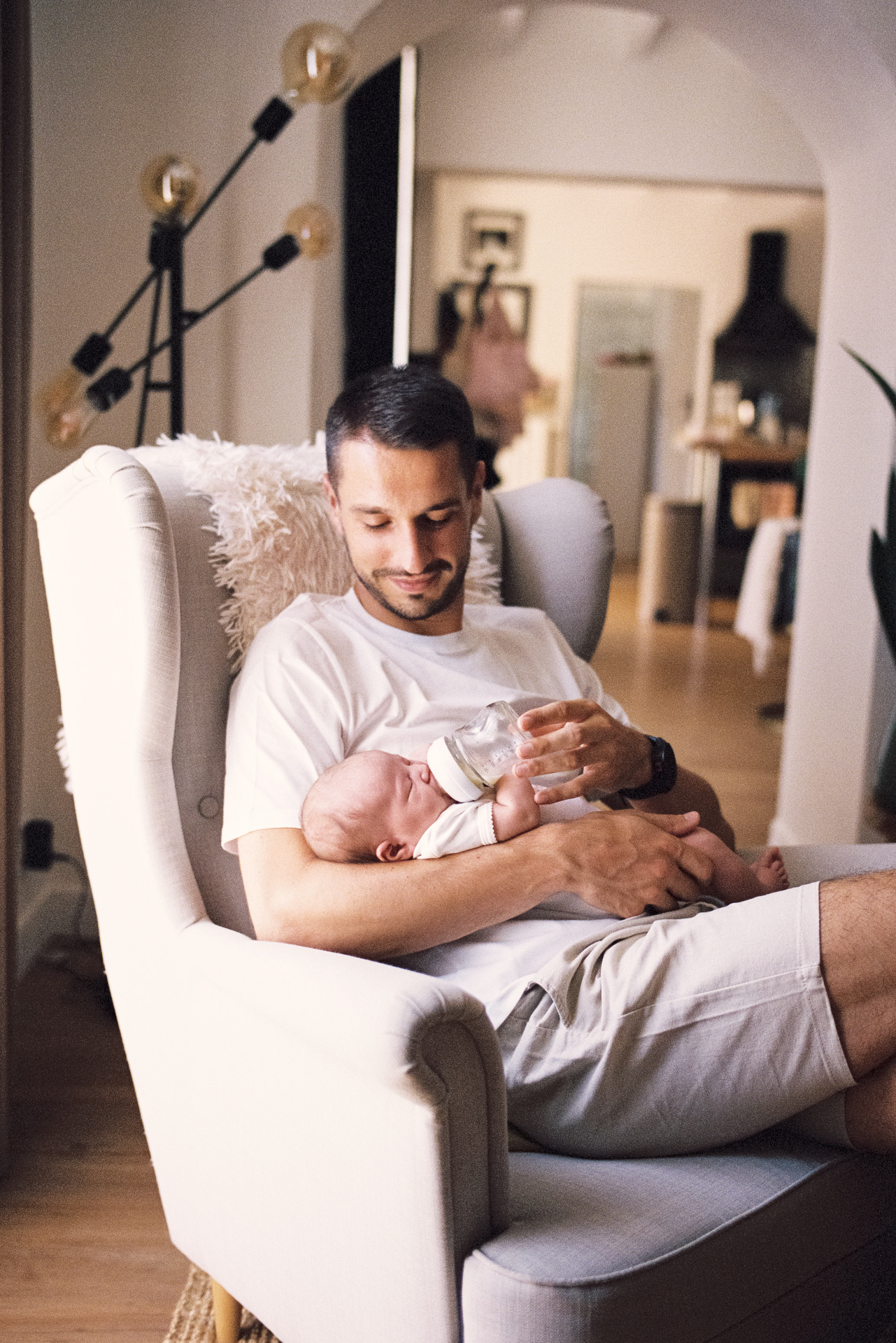 Papa donnant le biberon à son nouveau-né lors d’une séance photo à domicile