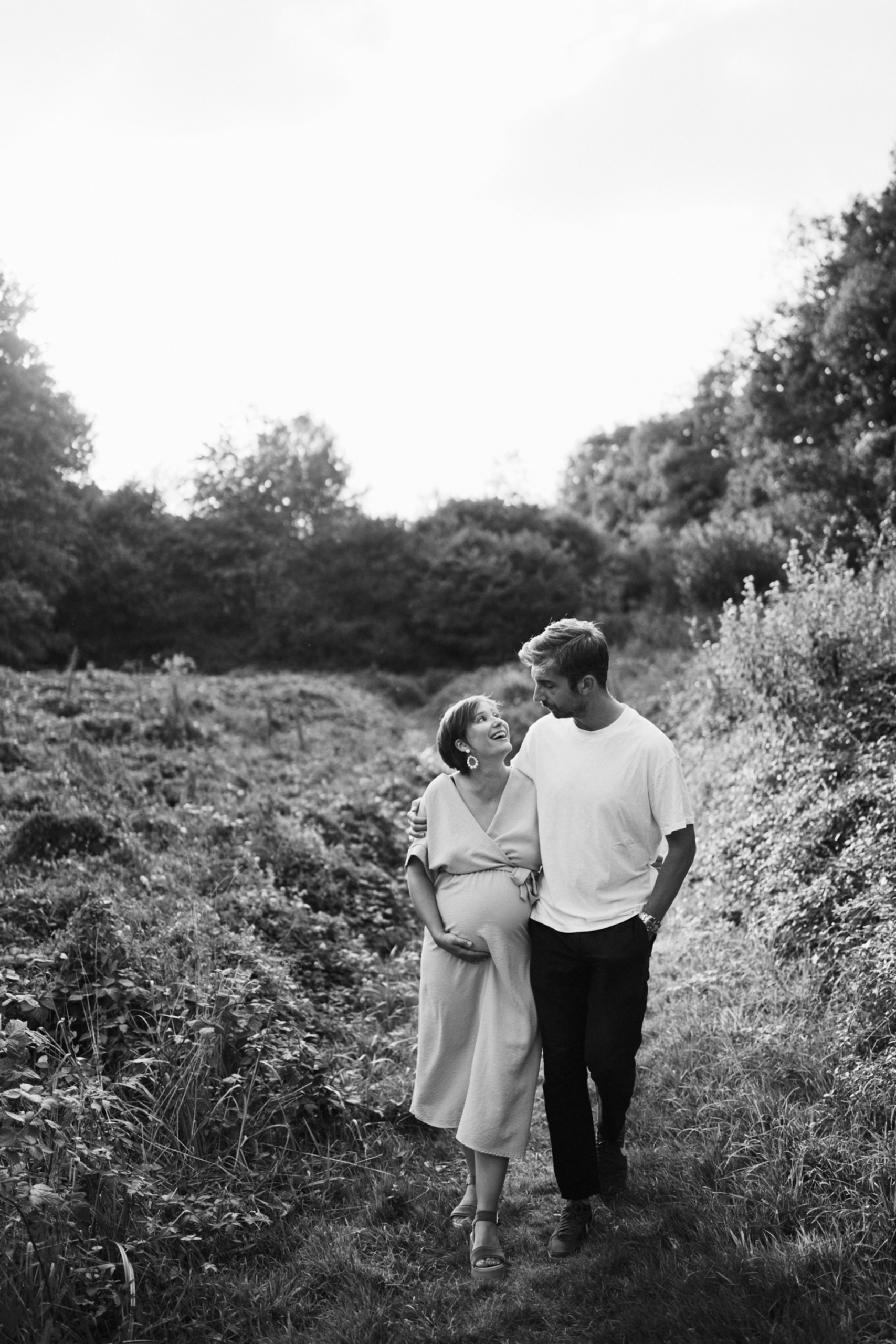 Mains posées sur le ventre d’une future maman lors d’une séance photo grossesse en noir et blanc